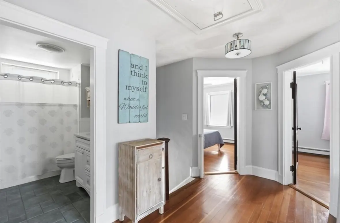 Second floor hallway with hardwood floors, full bath and bedroom doorways