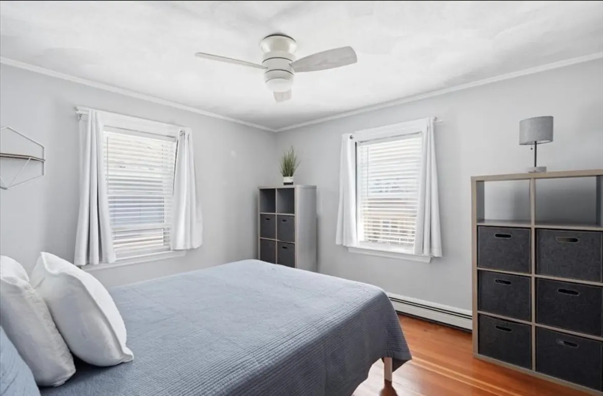 Primary bedroom with two windows, ceiling fan and hardwood floors